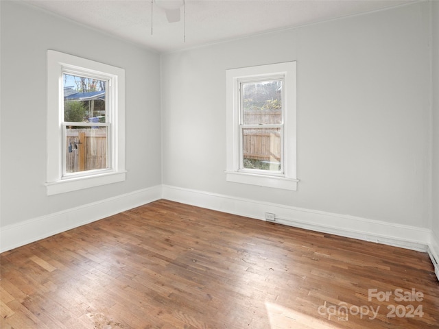 unfurnished room with a wealth of natural light, hardwood / wood-style flooring, and ceiling fan