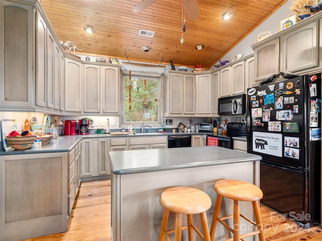 kitchen with black appliances, a kitchen bar, wood ceiling, vaulted ceiling, and light hardwood / wood-style floors