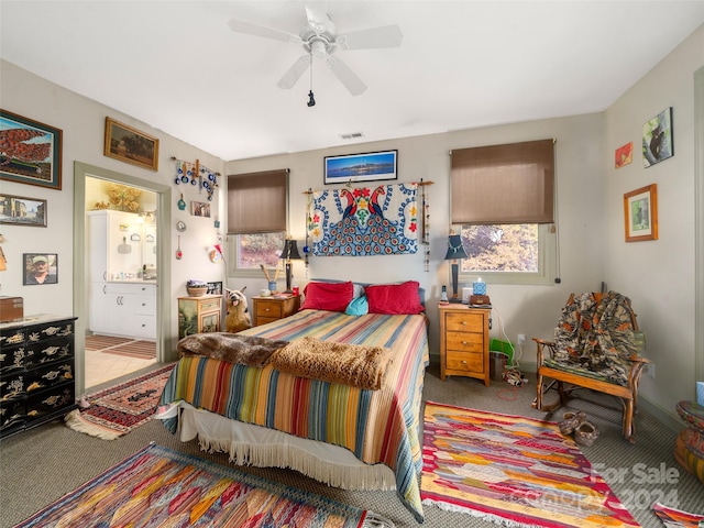 carpeted bedroom with ensuite bathroom and ceiling fan