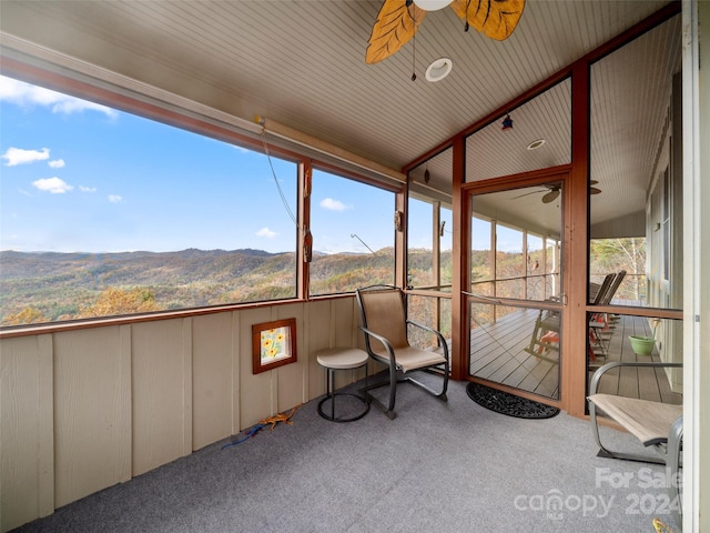 unfurnished sunroom featuring a mountain view and ceiling fan