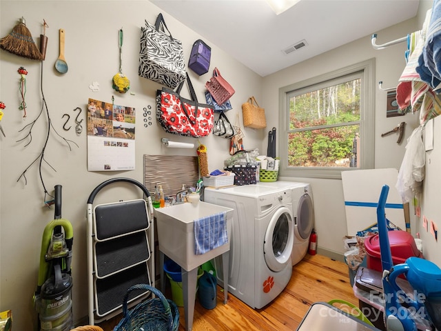 clothes washing area featuring light hardwood / wood-style floors and washer and clothes dryer