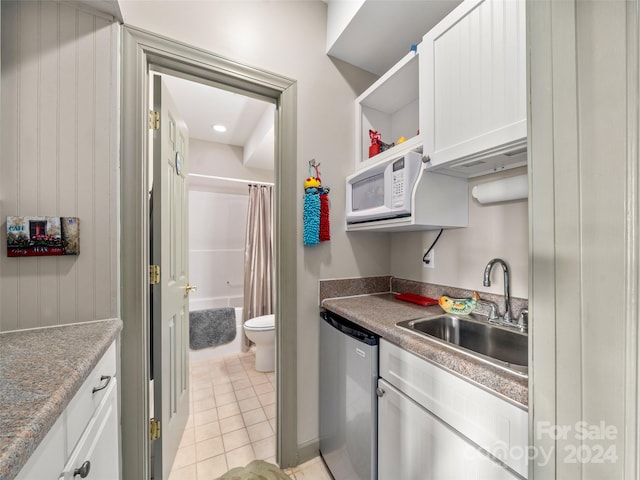 kitchen featuring stainless steel dishwasher, white cabinetry, sink, and light tile patterned floors