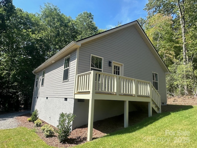 view of side of home with a deck and a lawn