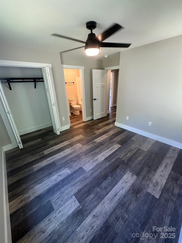 unfurnished bedroom featuring ensuite bath, dark hardwood / wood-style floors, ceiling fan, and a closet