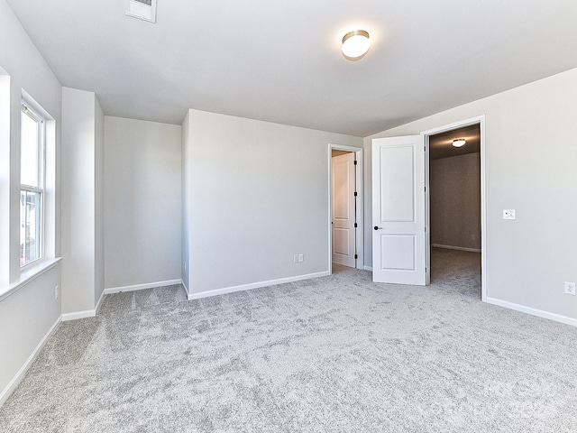 unfurnished room featuring light carpet and vaulted ceiling