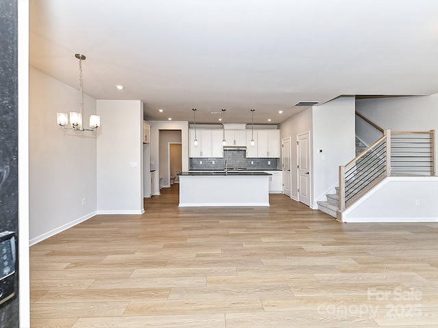 kitchen featuring decorative backsplash, white cabinets, hanging light fixtures, and an inviting chandelier