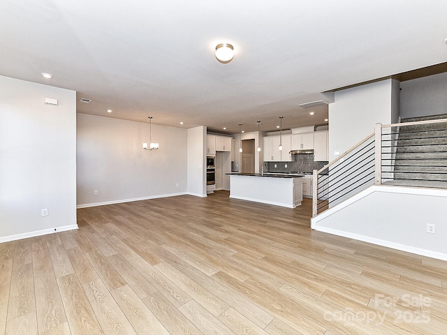 unfurnished living room with a chandelier, light hardwood / wood-style flooring, and sink