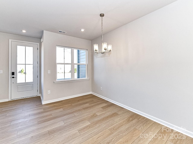 unfurnished dining area with light hardwood / wood-style flooring and an inviting chandelier