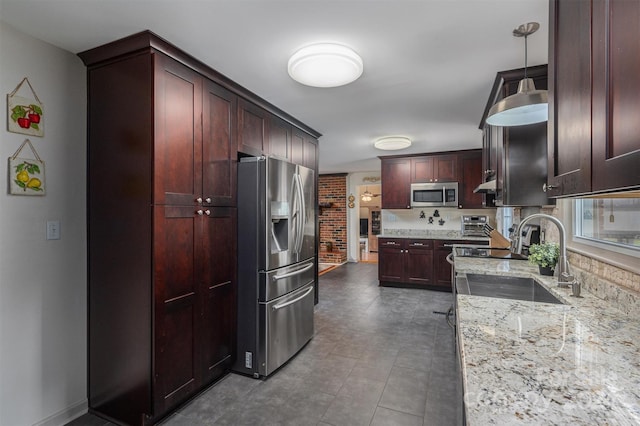 kitchen with stainless steel appliances, hanging light fixtures, sink, and light stone counters