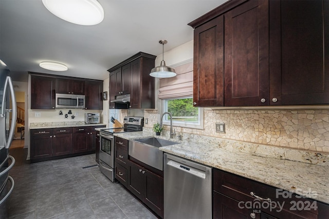 kitchen featuring stainless steel appliances, hanging light fixtures, sink, tasteful backsplash, and light stone countertops