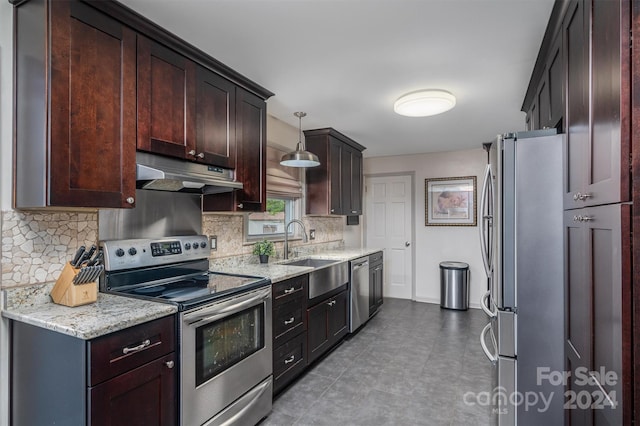 kitchen with light stone counters, appliances with stainless steel finishes, decorative light fixtures, decorative backsplash, and sink