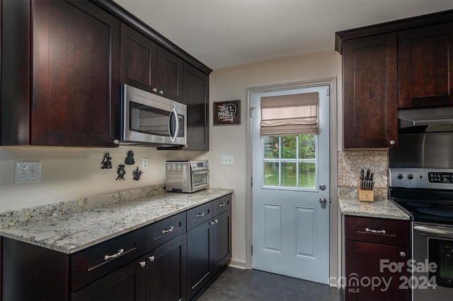 kitchen with light stone counters, dark tile patterned floors, dark brown cabinets, extractor fan, and appliances with stainless steel finishes