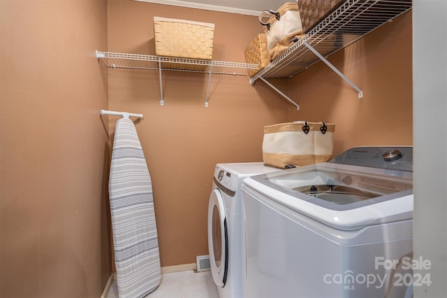 laundry area with light tile patterned flooring, washing machine and dryer, and crown molding