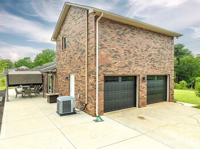 view of property exterior featuring central air condition unit, a garage, and a patio