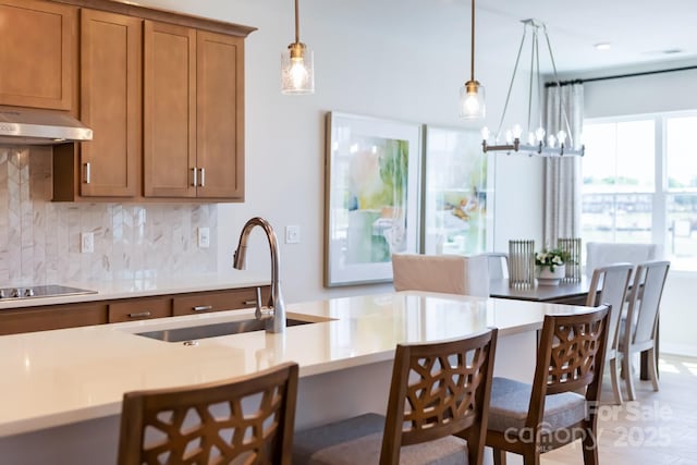 kitchen featuring decorative backsplash, pendant lighting, black electric cooktop, and sink