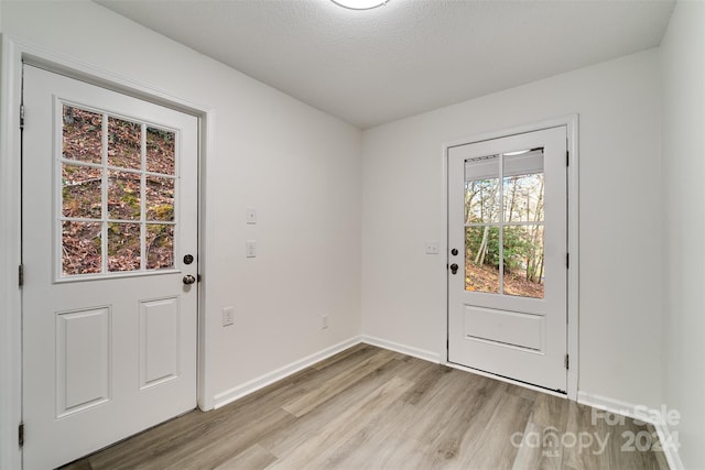 doorway to outside featuring a textured ceiling and light hardwood / wood-style flooring