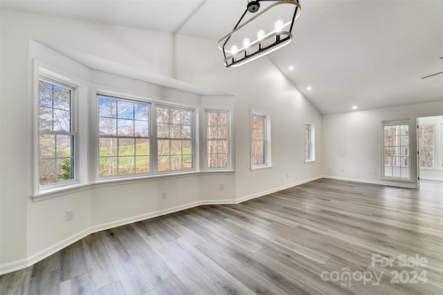 interior space featuring wood-type flooring, vaulted ceiling, and a healthy amount of sunlight