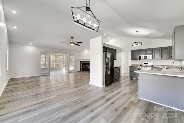 kitchen with light hardwood / wood-style flooring, hanging light fixtures, appliances with stainless steel finishes, and lofted ceiling