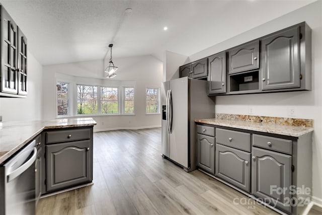 kitchen with appliances with stainless steel finishes, gray cabinets, decorative light fixtures, and lofted ceiling