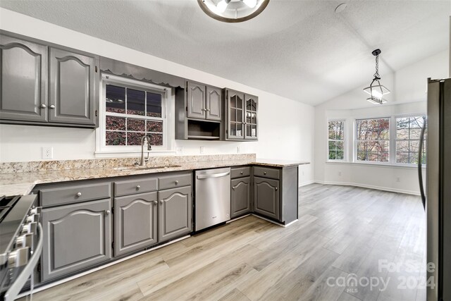 kitchen featuring appliances with stainless steel finishes, gray cabinetry, lofted ceiling, and sink