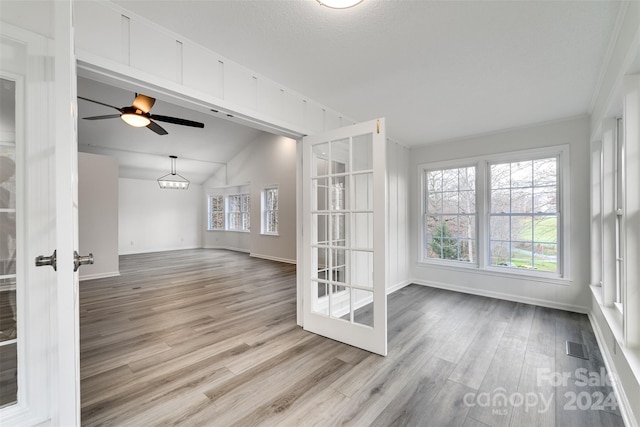 unfurnished room with ceiling fan, french doors, crown molding, lofted ceiling, and light wood-type flooring