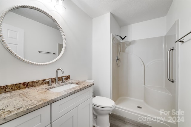 bathroom featuring a textured ceiling, toilet, hardwood / wood-style flooring, and a shower