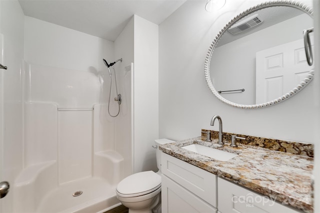 bathroom featuring a shower, vanity, and toilet