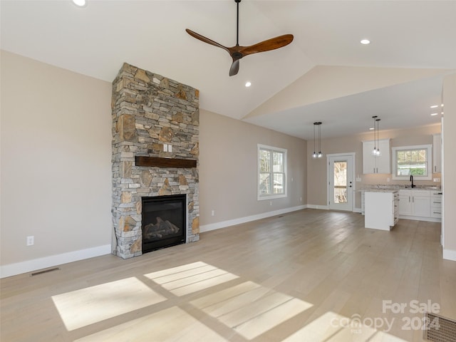 unfurnished living room featuring a fireplace, a wealth of natural light, light hardwood / wood-style flooring, and vaulted ceiling