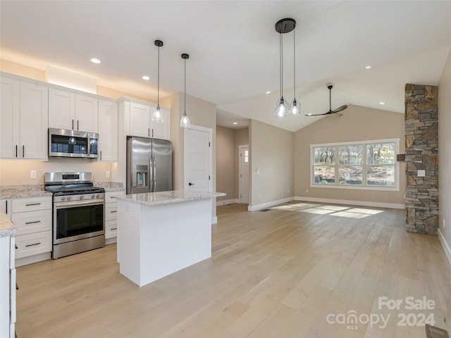 kitchen with stainless steel appliances, hanging light fixtures, a kitchen island, white cabinets, and vaulted ceiling