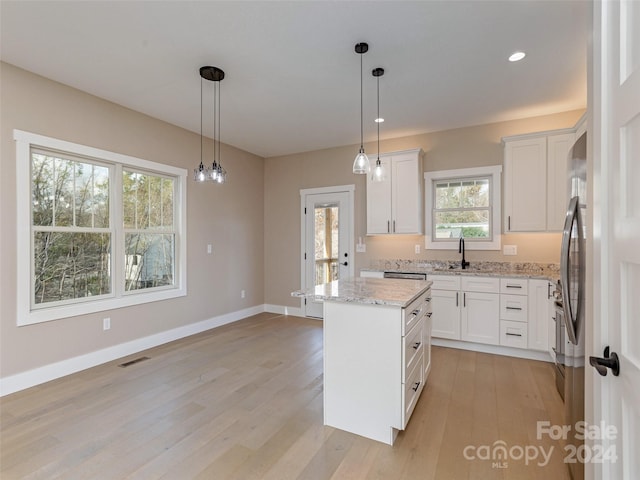 kitchen featuring light hardwood / wood-style flooring, a kitchen island, pendant lighting, and white cabinets