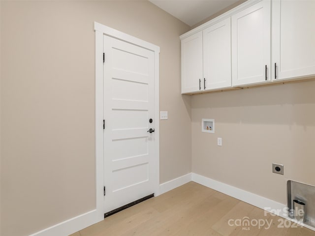 washroom with hookup for an electric dryer, light hardwood / wood-style floors, hookup for a washing machine, and cabinets