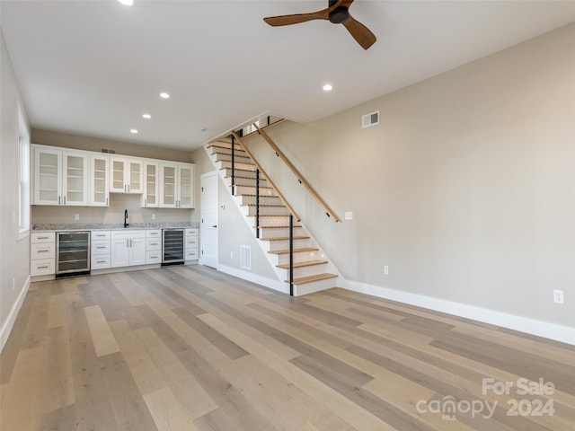 kitchen with wine cooler, white cabinetry, ceiling fan, and light hardwood / wood-style floors