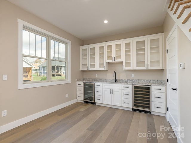 kitchen featuring light stone countertops, beverage cooler, light wood-type flooring, and white cabinetry