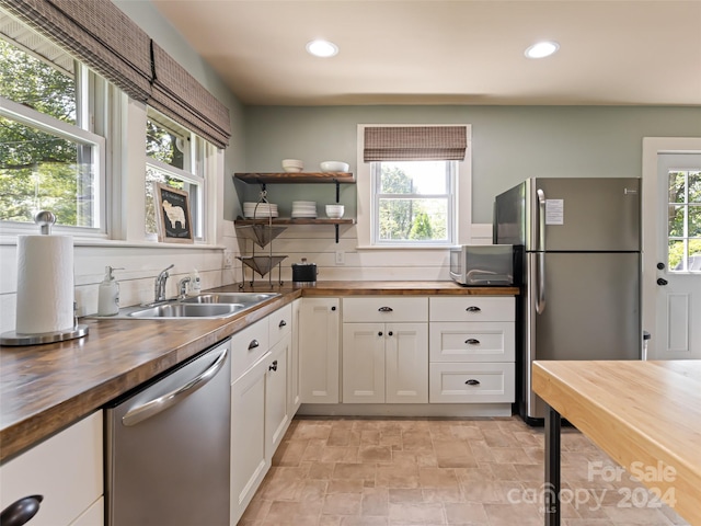 kitchen featuring wooden counters, white cabinetry, appliances with stainless steel finishes, and sink