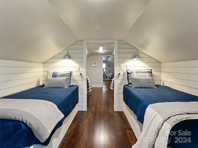 bedroom with dark hardwood / wood-style flooring, wood walls, and vaulted ceiling