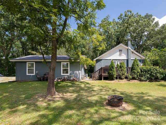 view of front of property featuring a front lawn, a wooden deck, and an outdoor fire pit