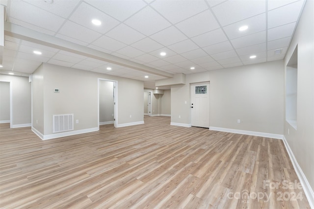 basement with a paneled ceiling and light hardwood / wood-style flooring