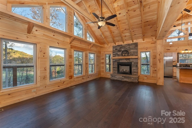 unfurnished living room featuring a stone fireplace, wood walls, beamed ceiling, dark hardwood / wood-style flooring, and wooden ceiling