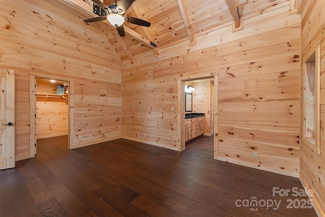 unfurnished room with dark hardwood / wood-style floors, wooden walls, vaulted ceiling with beams, ceiling fan, and wooden ceiling