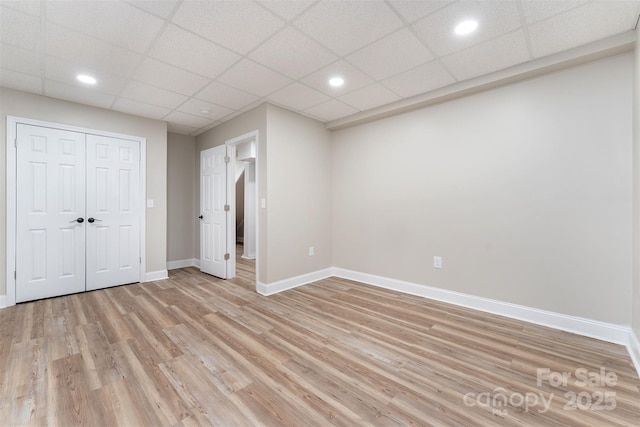 unfurnished bedroom featuring light hardwood / wood-style flooring, a closet, and a paneled ceiling