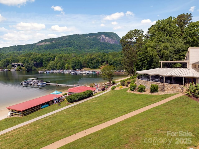 surrounding community featuring a lawn, a boat dock, and a water view