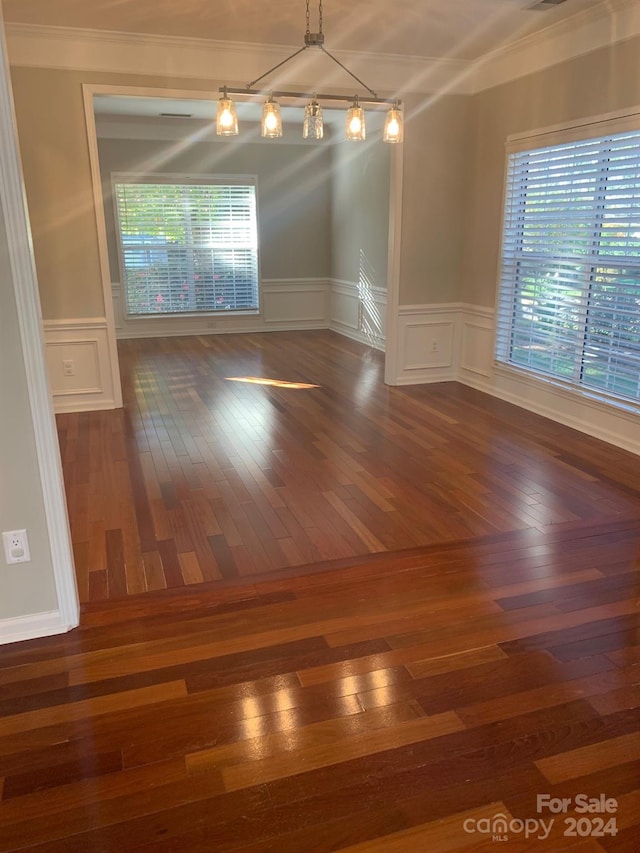 unfurnished dining area featuring crown molding and dark wood-type flooring