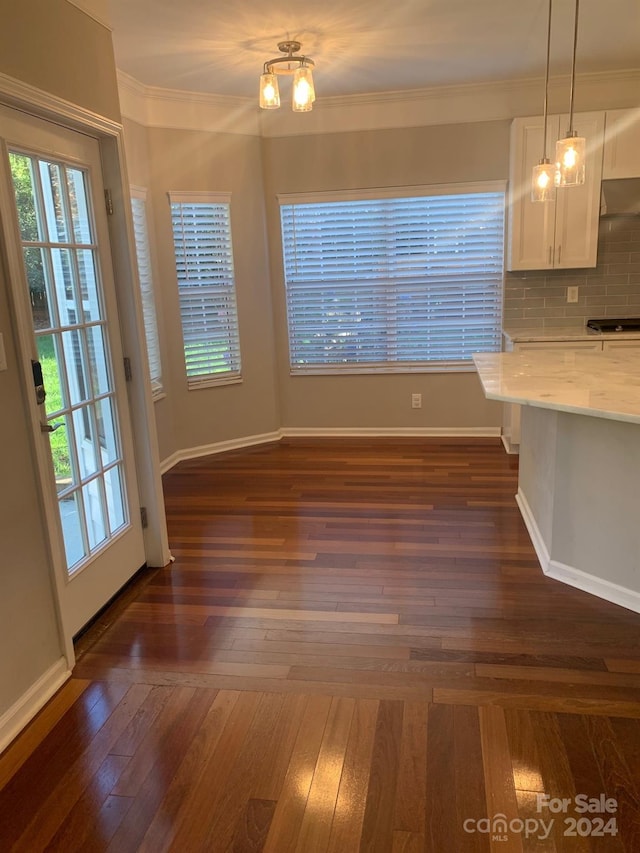 unfurnished dining area featuring crown molding, dark hardwood / wood-style flooring, and a notable chandelier