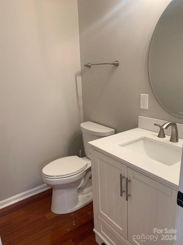 bathroom with wood-type flooring, vanity, and toilet