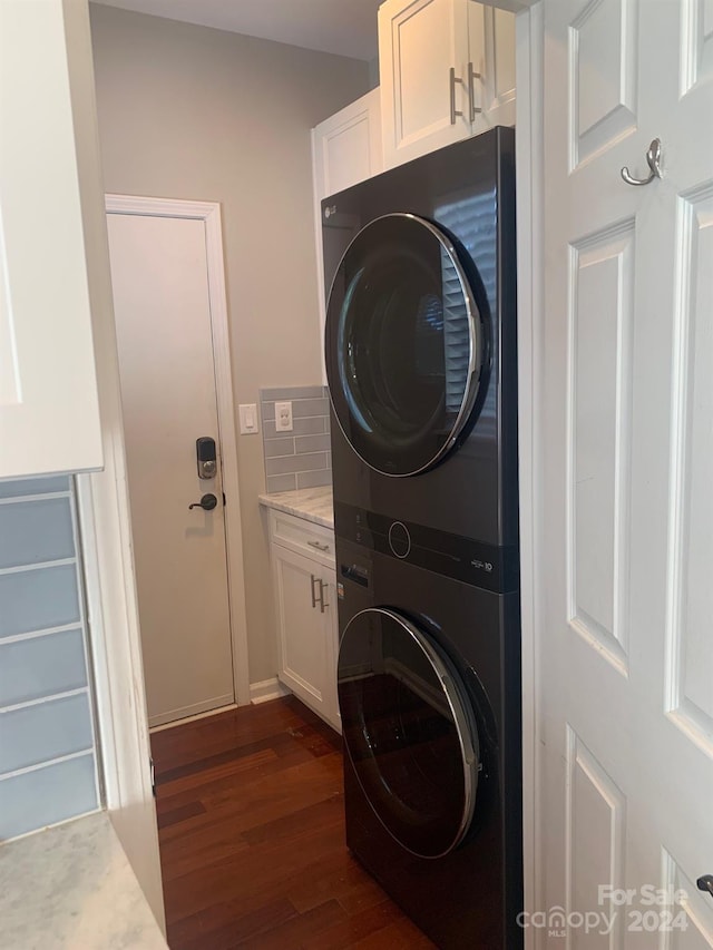 laundry room featuring cabinets, dark hardwood / wood-style flooring, and stacked washer and dryer