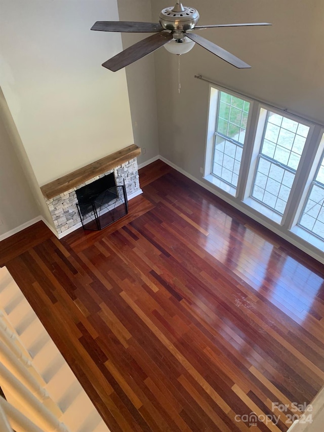 unfurnished living room featuring a fireplace, dark hardwood / wood-style floors, and ceiling fan