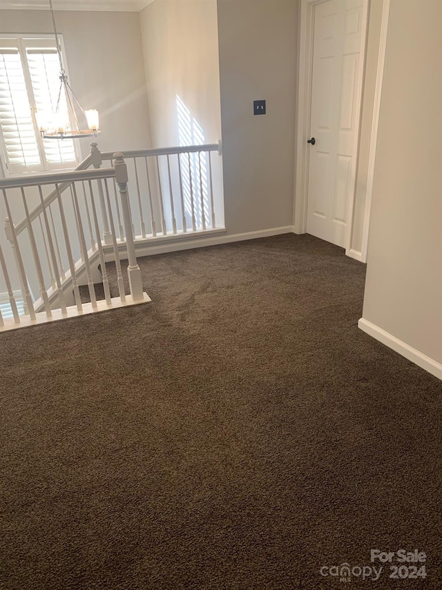 empty room with a chandelier and dark carpet