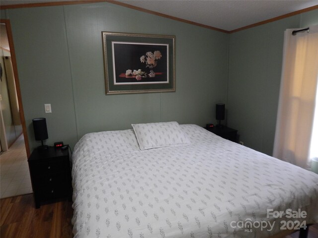 bedroom featuring wood-type flooring, crown molding, and lofted ceiling