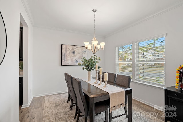 dining room featuring an inviting chandelier, light hardwood / wood-style flooring, and crown molding