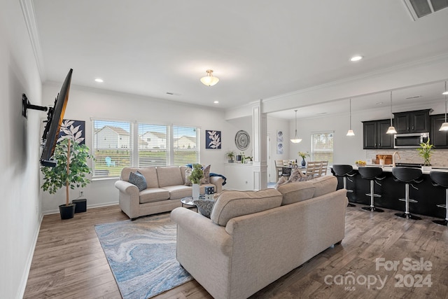 living room with a wealth of natural light, hardwood / wood-style floors, and ornamental molding